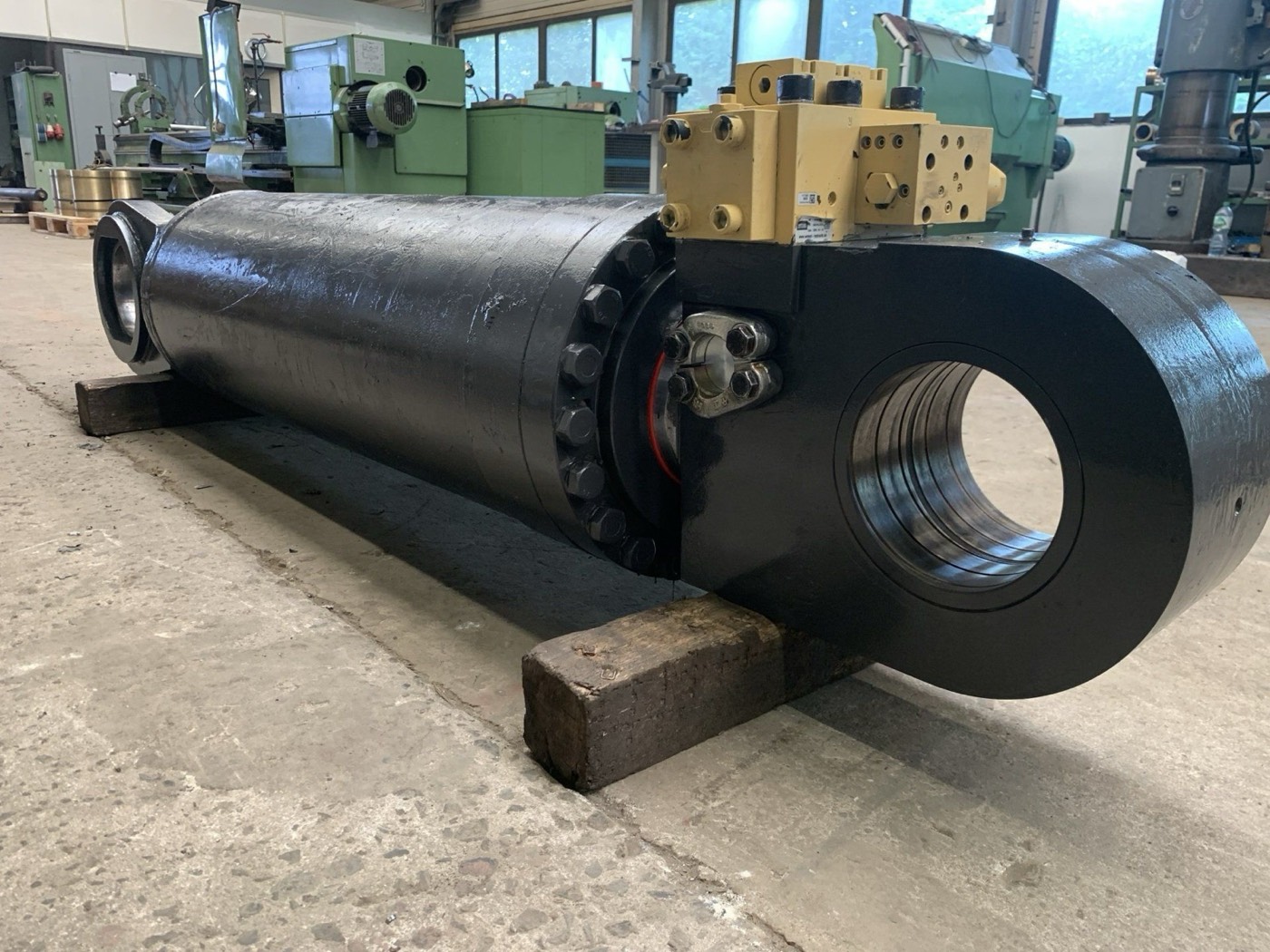 Großer schwarzer Hydraulikzylinder mit Ventilblock in der Werkhalle