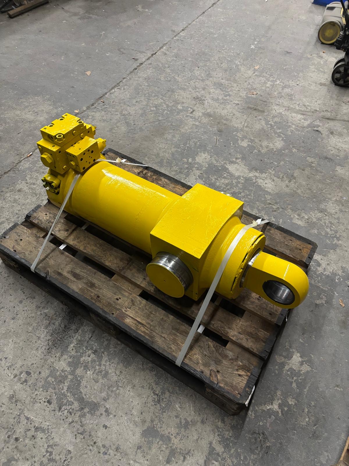 Gelber Hydraulikzylinder mit Ventilblock auf Palette