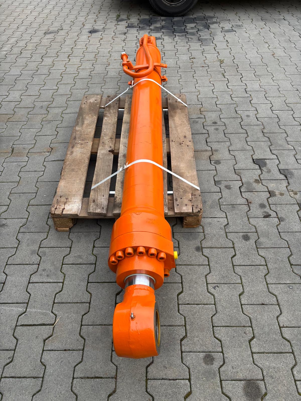 Langer orangefarbener Baumaschinen-Zylinder auf Palette