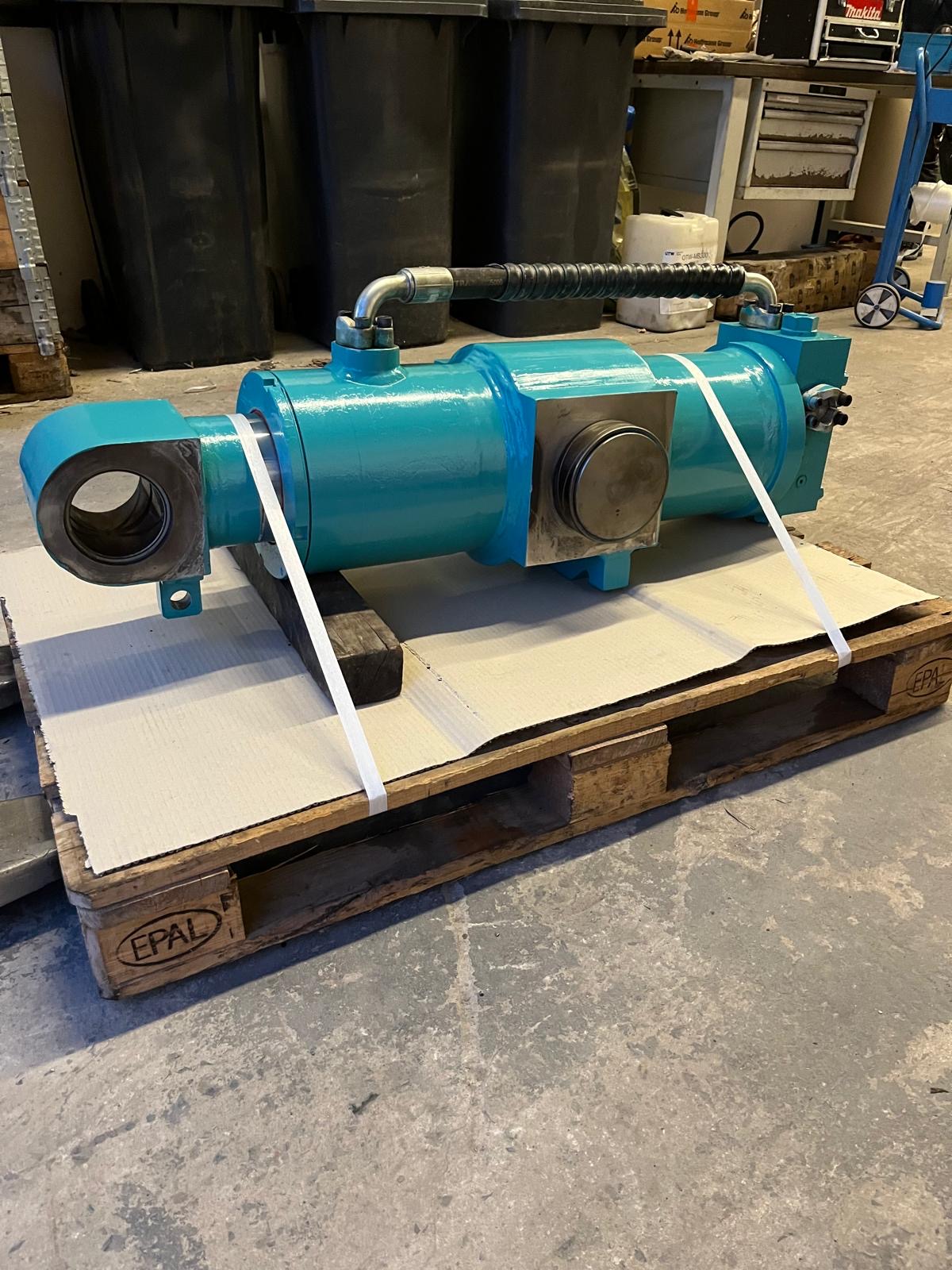 Türkiser Hydraulikzylinder mit Rohrleitung auf Palette