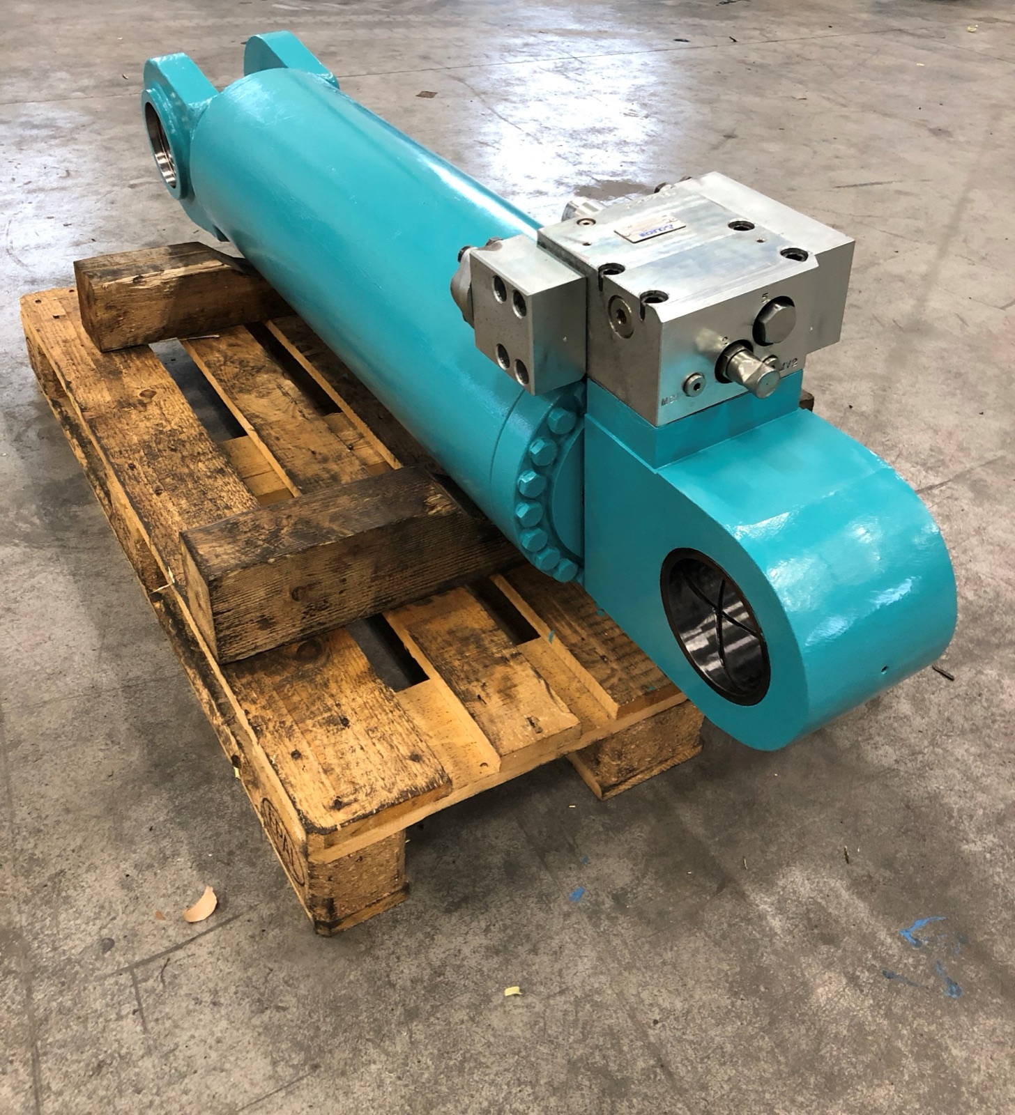 Türkiser Hydraulikzylinder mit Ventilblock auf Holzpalette